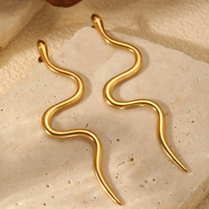 Elegant gold-tone stainless steel snake-shaped earrings on a textured stone display