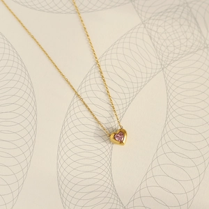 Detail of pink heart-shaped gemstone pendant on delicate 18K gold plated necklace
