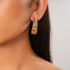 Close-up of tortoise shell patterned C-shape hoop earring worn on a model ear