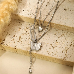 Close-up of silver butterfly pendant and round zircon stones on a layered necklace