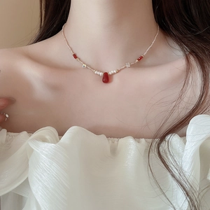 Detail of 18k gold plated necklace with pearls and a deep red teardrop pendant