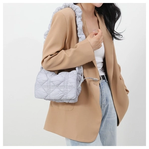 Detail of light gray quilted nylon crossbody bag with scrunchie style shoulder strap