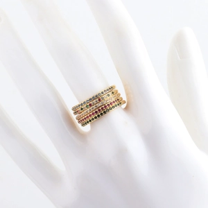 Detail of five stackable gold-plated rings with colorful cubic zirconia on a ceramic hand