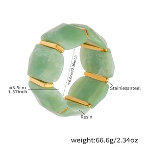 Dettaglio di blocchi di resina verde e barre d'acciaio dorato sul bracciale geometrico largo