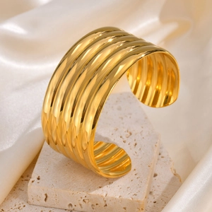 Macro detail of gold layered wavy cuff bracelet on silk and stone background