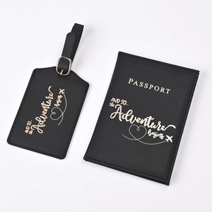 Detail of black faux leather passport holder and luggage tag set with gold foil lettering
