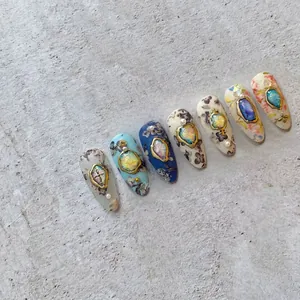 Macro shot of 5D vintage almond nail tips with gold-embossed floral patterns and pearls