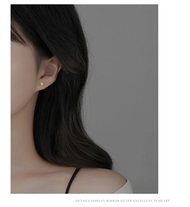 Detailed side view of a model wearing a delicate gold rose flower silver stud earring