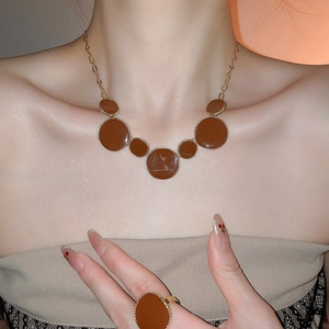 Gros plan d'un ensemble de bijoux en émail marron avec collier et bague à bordure dorée