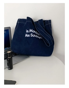 Détail du sac cabas en jean bleu foncé avec broderie blanche et accessoires de style