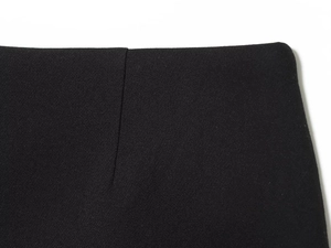 Close-up of black twill fabric texture and fine stitching on the waistline of the skirt