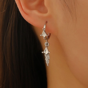 Close-up of a silver feather earring with geometric diamond charm worn on an ear