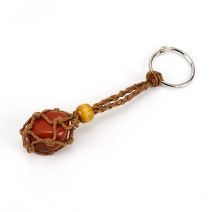 Macro detail of red jasper stone in a brown woven mesh net with a yellow bead keychain