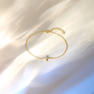 Close-up of golden S925 sterling silver chain with sparkling star charm on silk