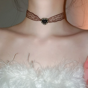 Close-up of brown lace choker with black heart pendant and pearl details on neck