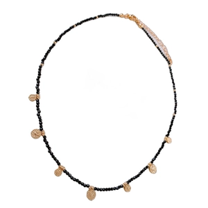 Vintage black beaded necklace with seven hammered gold pendants on a white background