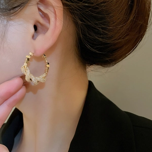 Close-up of model wearing twisted gold hoop earrings with sparkling cubic zirconia pavé