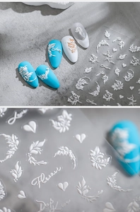 Detail of 3D embossed floral nail stickers on blue tips with white relief patterns