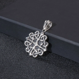 Macro detail of silver titanium steel cross pendant with intricate Celtic knot patterns