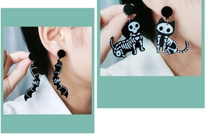Close-up of Halloween acrylic earrings featuring black bat and skeleton cat designs