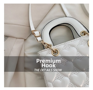 Close-up of white heart quilted bag with premium gold metal clasp and strap detail