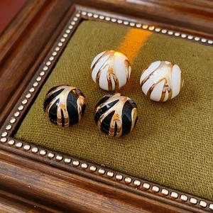 Vintage round enamel stud earrings with gold plating and swirl patterns in black and white
