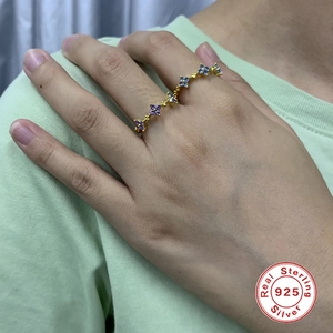 Detail of S925 sterling silver flower ring with purple and blue gems on finger