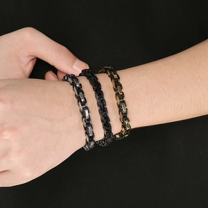 Detailed view of three Byzantine chain bracelets in silver, black, and gold for men