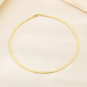 Close-up of golden stainless steel flat snake chain with lobster clasp on silk fabric