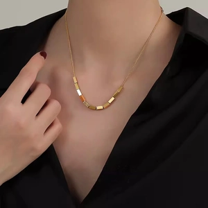 Minimalist gold square block pendant necklace shown on black clothing for women