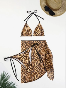 Flat lay of tiger print three-piece bikini set with sheer mesh sarong and beach accessories