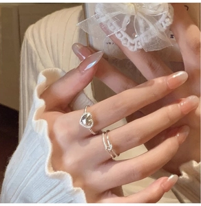Detailed view of silver heart stacking ring set worn with elegant white pleated cuff