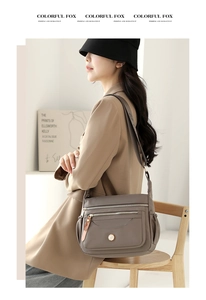 Detail view of charcoal gray waterproof nylon multi-zipper crossbody bag with logo