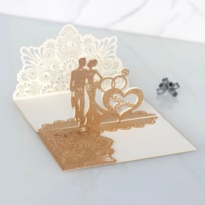 Detail of 3D laser-cut wedding card featuring gold glitter groom and bride silhouettes