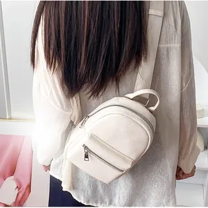 Detailed close-up of a white leather crossbody bag with silver zippers and lychee texture