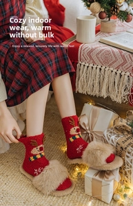 Close-up of fuzzy red reindeer Christmas socks paired with plush faux fur slippers