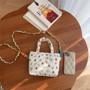 Detailed shot of quilted floral bear bag with colorful woven strap on a wooden table