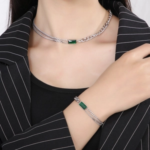 Silver titanium steel jewelry set with emerald green square stones worn by a model