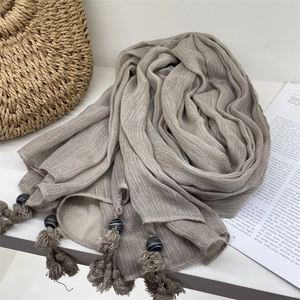 Detail shot of taupe voile scarf featuring handmade tassels and blue striped decorative beads