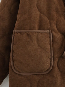 Detail van bruine corduroy gewatteerde jas met stiksels en zaktextuur