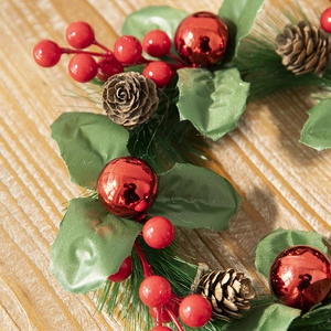 Christmas wreath with red berries, pine cones and glossy ornaments on a wooden table