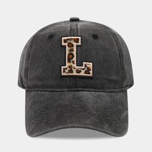 Detail of washed black baseball cap featuring a leopard print embroidered letter L patch