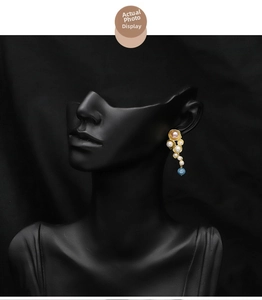Detailed close-up of long gold drop earrings featuring natural pearls and aquamarine stone
