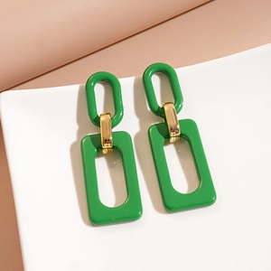 Close-up of green acrylic geometric dangle earrings with golden metal connectors and resin rings