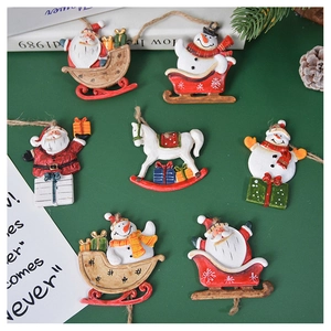 Detailed view of hand-painted resin Santa and Snowman sleigh ornaments on green background