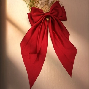 Detailed view of a vintage red silk bow hair clip with elegant long flowing ribbons