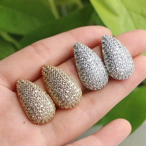 Luxe full-diamond teardrop earrings in gold and silver finish being held by hand