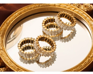 Detailed macro of gold-plated eternity rings with rectangular zircon stones on a mirror tray