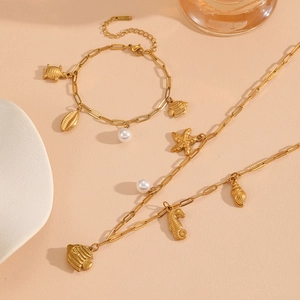 Detail of gold ocean-themed stainless steel necklace and bracelet with marine pendants