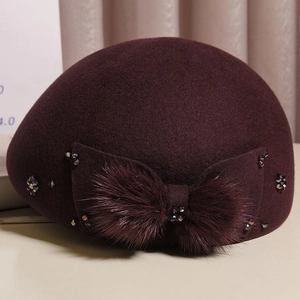 Detailed macro view of burgundy wool beret with plush bow and beaded crystal accents